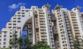 A high rise modern apartment complex in suburban Bangalore against a blue sky on a sunny day.