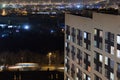 High-rise modern building in the evening window lights.Casual urban city life. Traffic on the road.From tower rooftop Royalty Free Stock Photo