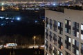 High-rise modern building in the evening window lights.Casual urban city life. Traffic on the road.From tower rooftop Royalty Free Stock Photo