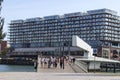 High rise modern glass apartment building in downtime urban city environment with peopl walking across a bridge Royalty Free Stock Photo