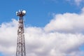 A high-rise telecommunications tower made of metal structure against a blue sky with gray clouds. Background Royalty Free Stock Photo