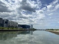 High-rise tenement buildings reflected on a huge and murky river under thick dark clouds.