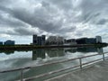 High-rise tenement buildings reflected on a huge and murky river under thick dark clouds.