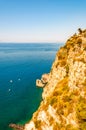 High rocky cliff above vibrant pure water of Tyrrhenian sea bay with floating boats near Meta and Sorrento cities Royalty Free Stock Photo