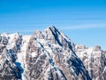 High rocky snowy peak on sunny winter day with blue sky. Alpine mountain ridge Royalty Free Stock Photo