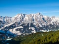 High rocky snowy peak on sunny winter day with blue sky. Alpine mountain ridge Royalty Free Stock Photo