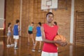 High school boy holding a basketball while team playing in background Royalty Free Stock Photo