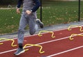 Runner running over yellow mini hurdles on a red track