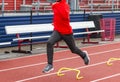 High school boy running over yellow mini hurdles on a track