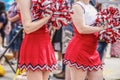 High school cheerleaders with pompoms an shirt red and white uniforms in parade with blurred crowd in the background - cropped and