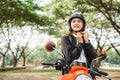 High school girl tightens helmet strap while riding motorbike