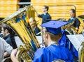 High school graduating senior plays horn in the band in cap and gown