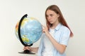 A high school student holds a globe in her hands and carefully examines it.exam. Geography. World. Earth. Thoughtful