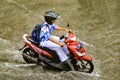 a high school student who rides a motorbike who drives through flood waters during heavy rain in a residential area Royalty Free Stock Photo