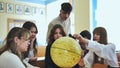 High school students looking at the yellow globe of the moon.