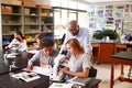 High School Students With Tutor Using Microscope In Biology Class