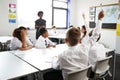High School Students Wearing Uniform Raising Hands To Answer Question Set By Teacher In Classroom Royalty Free Stock Photo