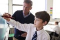 High School Teacher With Male Student Wearing Uniform Using Interactive Whiteboard During Lesson Royalty Free Stock Photo