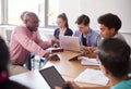 High School Teacher Talking To Pupils Using Digital Devices In Technology Class