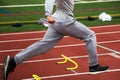 Legs of runner running over yellow mini hurdles on a red track