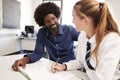 High School Tutor Giving Uniformed Female Student One To One Tuition At Desk In Classroom