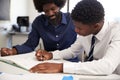 High School Tutor Giving Uniformed Male Student One To One Tuition At Desk In Classroom Royalty Free Stock Photo