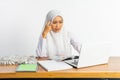 high school veiled girl at desk thinking while using laptop Royalty Free Stock Photo