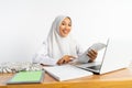 high school veiled girl smiling at desk carrying book