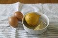 High shot of lemons inside a white bowl with 2 organic eggs