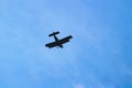 High in sky is  silhouette of single-engine biplane with brace wing. Plane is diving. Royalty Free Stock Photo