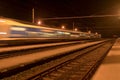 High speed passenger train on tracks with motion blur effect at night. Railway station in the Czech Republic
