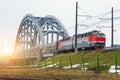 High speed red passenger train rushing through the bridge industrial railway in the evening at sunset. Royalty Free Stock Photo