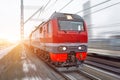 High-speed red passenger train rushing through the railway in the evening at sunset. Royalty Free Stock Photo