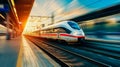 High speed train in motion on the railway station at sunset. Fast moving modern passenger train on railway platform. Railroad with Royalty Free Stock Photo