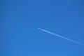 High speed white passenger plane flying at high altitude over clear blue sky leaving two white contrails Royalty Free Stock Photo