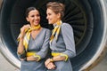 Joyous flight attendants standing by the turbofan engine