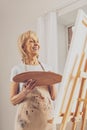 Happy senior female person looking at her easel