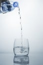 A high stream of clean drinking water flows from the bottle into a clear glass. Royalty Free Stock Photo