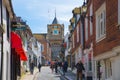 High street of Old Rye town with periodic buildings, lots of people and cars parked on side.