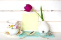 High Tea Time with Stack of Colorful Teacups, Purple Tulip in Vase, fork and spoon, with light green menu card on White Wood Board Royalty Free Stock Photo