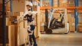 High-Tech Futuristic Warehouse: Worker Wearing Advanced Full Body Powered exoskeleton Exosuit. Hel