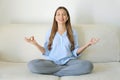 High-Tech Meditation. Young woman with wireless earphones using meditation app on smart phone sitting in lotus position on Royalty Free Stock Photo