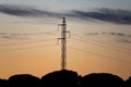 High tension tower with cables over forest at dusk
