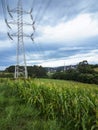 High tension tower placed in a corn field with the power lines flying over the fields from the power plant in the background, Royalty Free Stock Photo