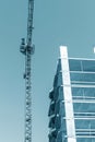 High tower crane standing near building under construction against blue sky background Royalty Free Stock Photo