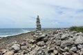 A high tower of flat stones stands on the seashore in cloudy weather