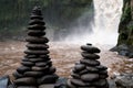 High towers of flat stones cairn laid out on the bank at the waterfall. Traditions of Buddhism.