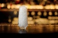 High transparent cocktail glass with ice cubes on the bar counter of pub