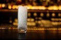 High transparent glass filled with ice cubes on the bar counter of restaurant in blurred background