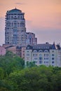 High urban high-rise buildings against the background of green trees and the evening sky